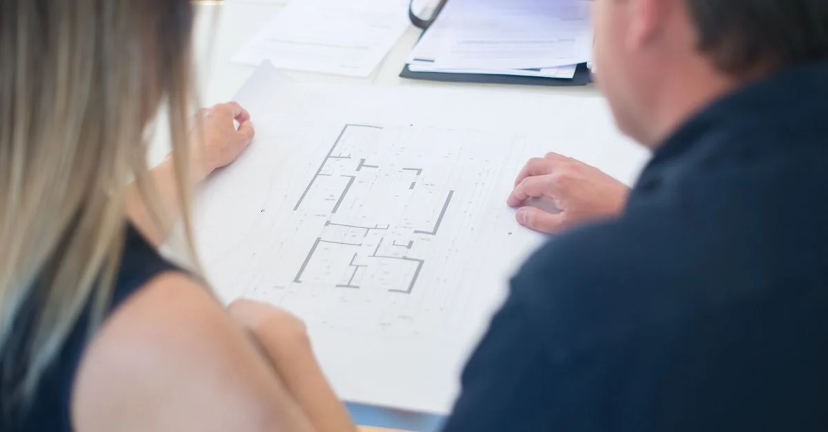 Architectes discutant d'un plan de sol détaillé dans un bureau, vu d'en haut.