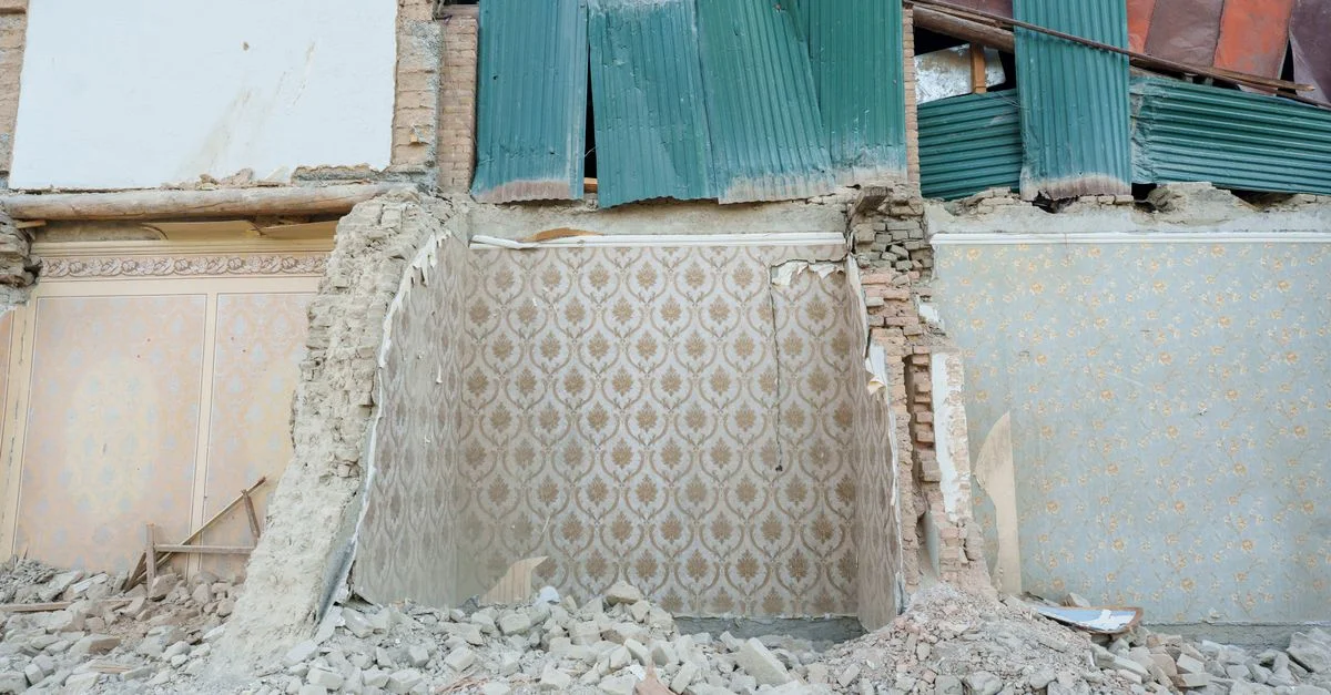 Image d'un bâtiment abandonné en cours de démolition à Samarcande, montrant du papier peint apparent et des décombres.