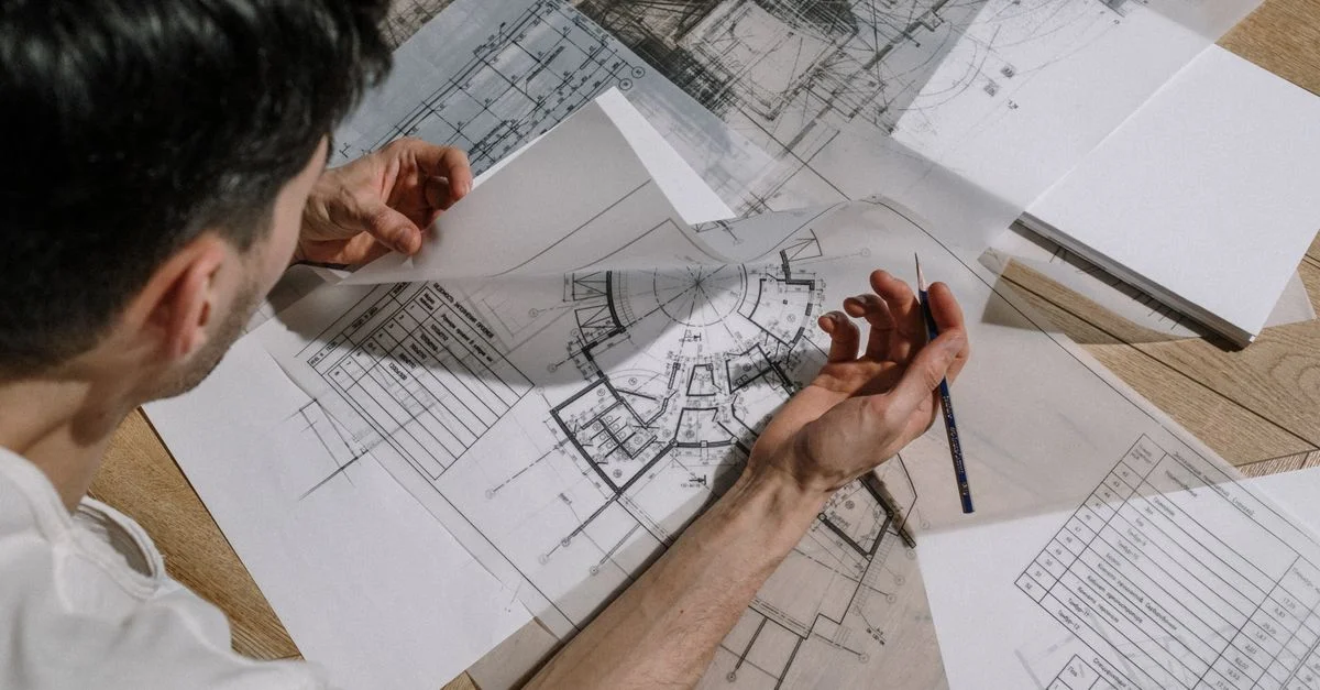 Architecte étudiant et esquissant des plans architecturaux détaillés à l'intérieur.