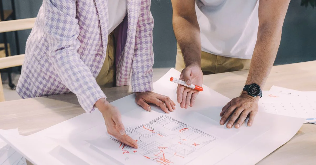 Deux architectes brainstorment sur des plans d'étage dans un bureau moderne.