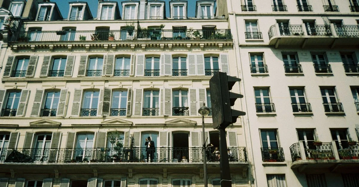 Un bâtiment classique avec balcons et fenêtres dans une rue d'une ville européenne.